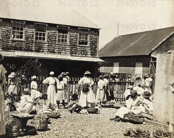 Outside the 'Standard Rum Shop'. Traders sell their wares from baskets outside the 'Standard Rum Shop'. Scarborough, Tobago, circa 1912. Scarborough, Trinidad and Tobago, Trinidad and Tobago, Caribbean, North America .