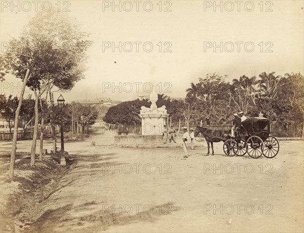 A road junction in Cuba. A horse-drawn coach approaches an empty road junction with a monument at its centre. Four uniformed men, possibly police officers, stand nearby. Cuba, circa 1927. Cuba, Caribbean, North America .
