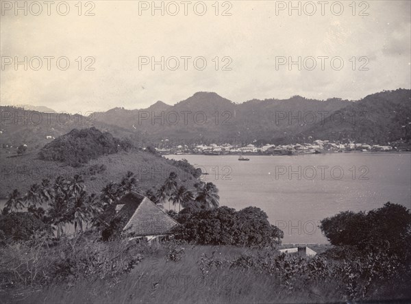 A bay in St Lucia. A coastal settlement nestles in the foothills of mountains across a bay in St Lucia. St Lucia, circa 1896. St Lucia, Caribbean, North America .