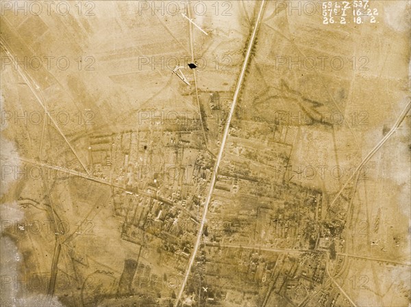 Aerial view of a bomb-damaged village. One of a series of British aerial reconnaissance photographs recording the positions of trenches on the Western Front during the First World War. A bomb-damaged village is intersected by a prominently straight road, possibly one of several Roman roads in the region. Nord-Pas de Calais or Picardie, France, 26 February 1918., Nord-Pas de Calais, France, Western Europe, Europe .