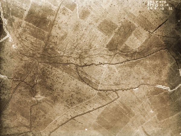 Aerial view of a front line system. One of a series of British aerial reconnaissance photographs recording the positions of trenches on the Western Front during the First World War. Shell craters pepper the fields surrounding a front line trench, probably British, which runs west to east. An original caption identifies the area to the north as no man's land. Nord-Pas de Calais or Picardie, France, 26 February 1918., Nord-Pas de Calais, France, Western Europe, Europe .