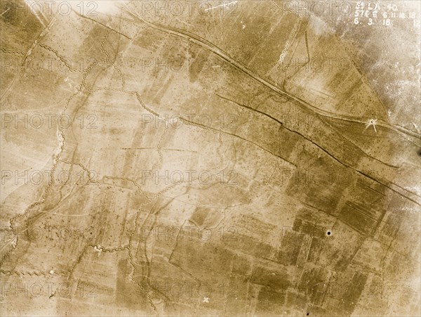 Aerial view of a front line trench. One of a series of British aerial reconnaissance photographs recording the positions of trenches on the Western Front during the First World War. A small white circle on the main road indicates the explosion point of a mine and a front line trench, probably British, runs north to south, protected by a belt of barbed wire. Nord-Pas de Calais or Picardie, France, 6 March 1918., Nord-Pas de Calais, France, Western Europe, Europe .
