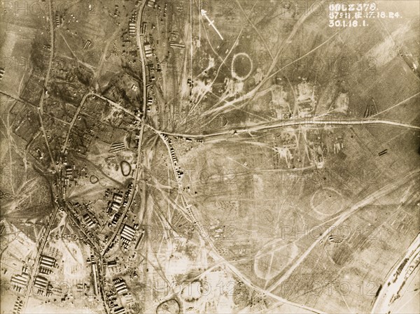 British military camp in a ruined village. One of a series of British aerial reconnaissance photographs recording the positions of trenches on the Western Front during the First World War. A British military camp, based in the ruins of a bomb-damaged village. An original caption identifies the positions of transport wagons, Nissen huts and horse standings in the bottom left hand corner. Nord-Pas de Calais or Picardie, France, 30 January 1918., Nord-Pas de Calais, France, Western Europe, Europe .