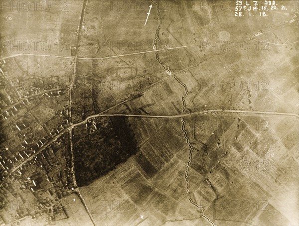 Ruined village behind a British defence trench. One of a series of British aerial reconnaissance photographs recording the positions of trenches on the Western Front during the First World War. A bomb-damaged village lies behind a British defence trench, which zig-zags its way across the fields protected by a line of barbed wire. An original caption identifies the positions of a number of field guns, stationed beside the roads leading into the village. Nord-Pas de Calais or Picardie, France, 28 January 1918. France, Western Europe, Europe .