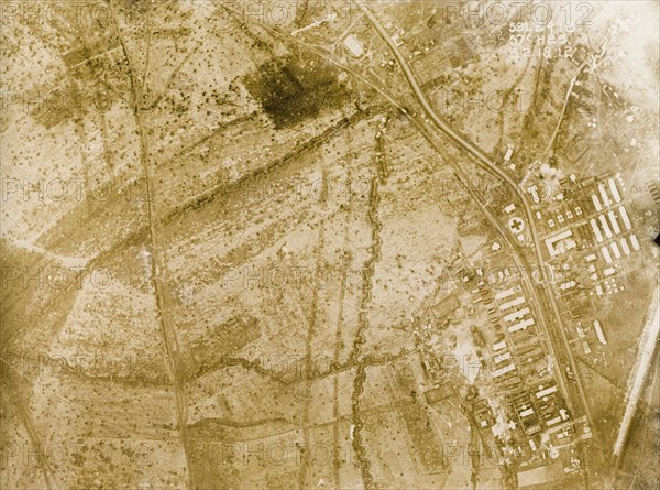 Aerial view of a military base and field hospital. One of a series of British aerial reconnaissance photographs recording the positions of trenches on the Western Front during the First World War. Fields surrounding a military camp, probably British, is riddled with square-toothed trenches and bomb craters. An original caption points out a field hospital on the right, presumably the building marked with a cross. Nord-Pas de Calais or Picardie, France, 3 February 1918., Nord-Pas de Calais, France, Western Europe, Europe .