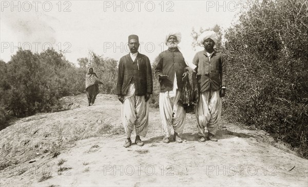 Khan Laghari with his two sons. An elderly Indian man, identified as Khan Laghari, walks along a rural road with his two sons. All wear traditional Indian dress including 'dhotis' and turbans. Probably Sind, India (Sindh, Pakistan), circa 1910., Sindh, Pakistan, Southern Asia, Asia.