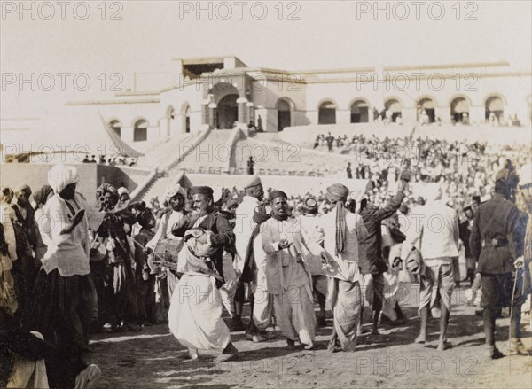 Musicians and dancers in Sukkur. Musicians and dancers perform to a crowd of spectators at an outdoor event. Sukkur, Sind, India (Sindh, Pakistan), circa 1908. Sukkur, Sindh, Pakistan, Southern Asia, Asia.