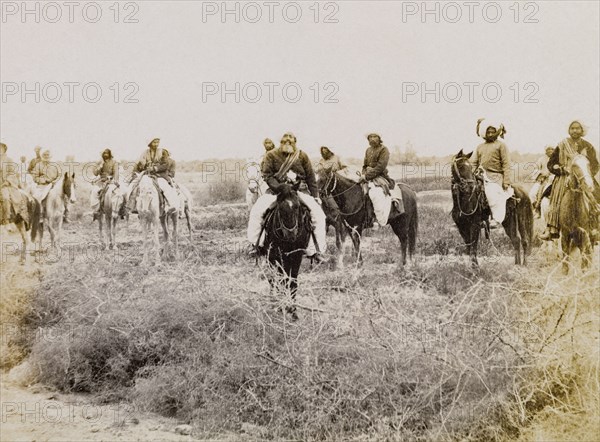 Indian men on horseback. A group of men in traditional Indian dress ride through a scrub landscape on horseback. Sukkur, Sind, India (Sindh, Pakistan), circa 1908. Sukkur, Sindh, Pakistan, Southern Asia, Asia.