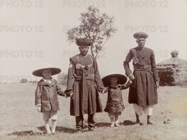 The Lawrence boys with Indian attendants. George (b.1899) and Henry (b.1902), the sons of Phyllis and Sir Henry Staveley Lawrence (a British civil servant), hold hands with two traditionally dressed Indian attendants. India, circa 1905. India, Southern Asia, Asia.