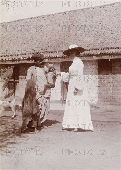 Phyllis Lawrence greets a farm worker's family. Phyllis Louise Lawrence, the first wife of Sir Henry Staveley Lawrence (Collector of Karachi), greets an Indian farm labourer and his children during a visit to farm stables in Karachi. Karachi, Sind, India (Sindh, Pakistan), circa 1910. Karachi, Sindh, Pakistan, Southern Asia, Asia.