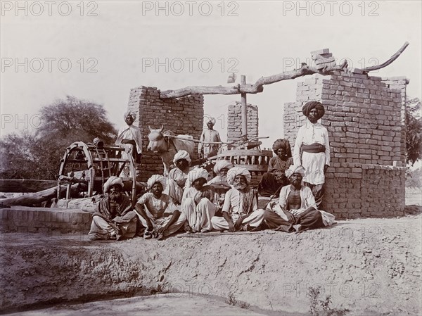A bullock-driven water wheel, India. A group of Indian labourers pose for an outdoor portrait beside a bullock-driven water wheel. India, circa 1925. India, Southern Asia, Asia.