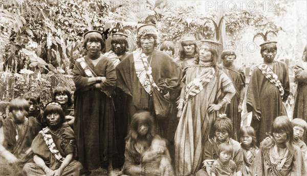 Peruvian men, women and children. A group of indigenous Peruvian men, women and children pose outdoors for a group portrait in the Ancon District of Lima. They wear traditional dress including sashes worn across their bodies and distinctive flat hats decorated with feathers. Lima, Peru, circa 1920. Lima, Lima Metropolitana, Peru, South America, South America .