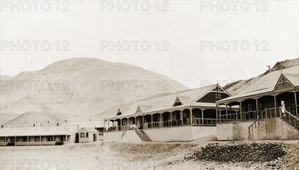 Colonial buildings on San Lorenzo Island . A number of single-storey, colonial-style buildings with verandas, situated below a mountain on San Lorenzo Island. San Lorenzo Island, Peru, circa 1920. San Lorenzo Island, Callao, Peru, South America, South America .