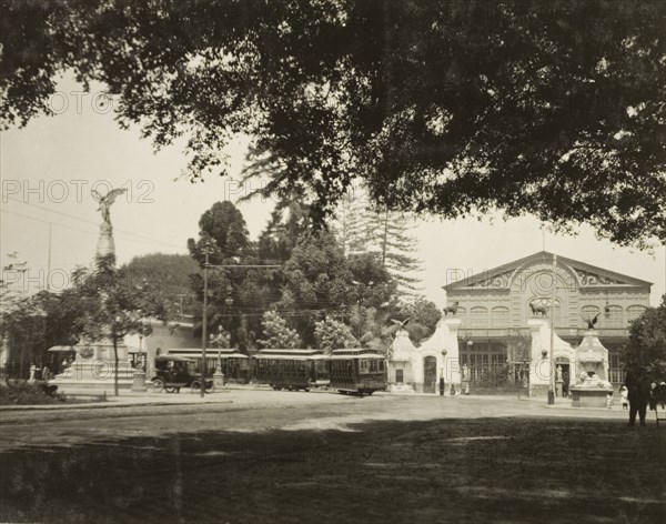 A street tram in Lima. A tram travels around the corner of a street in Lima, past a grand, colonial-style building and a stone monument topped with the statue of a winged figure. Lima, Peru, circa 1920. Lima, Lima Metropolitana, Peru, South America, South America .