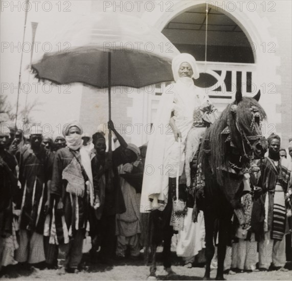 An Etsu Nupe during Sallah celebrations. An Etsu (ruler) Nupe dressed in full ceremonial attire rides a caparisoned horse during celebrations for Sallah, an Islamic event held to mark the end of Ramadan. Bida, Nigeria, October 1948. Bida, Niger, Nigeria, Western Africa, Africa.