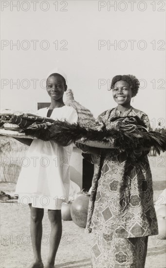 Nigerian gifts for Queen Elizabeth II. Two adolescents from Kaduna Children's Village prepare to present Queen Elizabeth II with a selection of traditional Nigerian gifts during her royal visit to Kaduna. Kaduna, Nigeria, 1956. Kaduna, Kaduna, Nigeria, Western Africa, Africa.