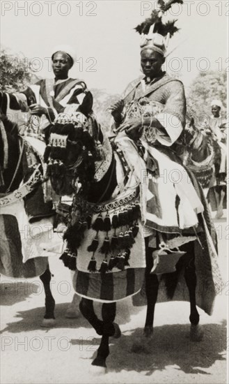 Nigerian chief riding a caparisoned horse. A Nigerian chief wearing an elaborate feathered headdress rides a caparisoned horse during celebrations for Sallah, an Islamic event held to mark the end of Ramadan. Nigeria, circa 1948. Nigeria, Western Africa, Africa.