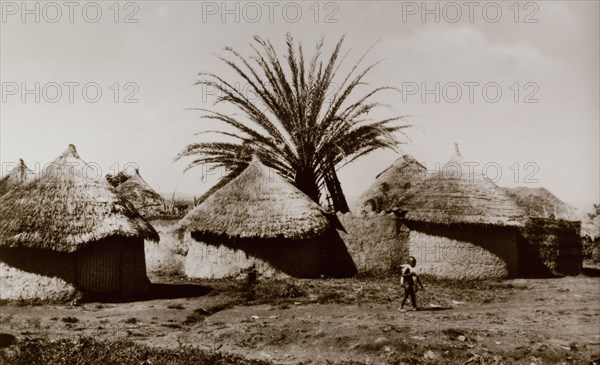 A Hausa village. A series of round huts with mud walls and thatched roofs form the outer wall of a Hausa village. Northern Nigeria, circa 1940. Nigeria, Western Africa, Africa.