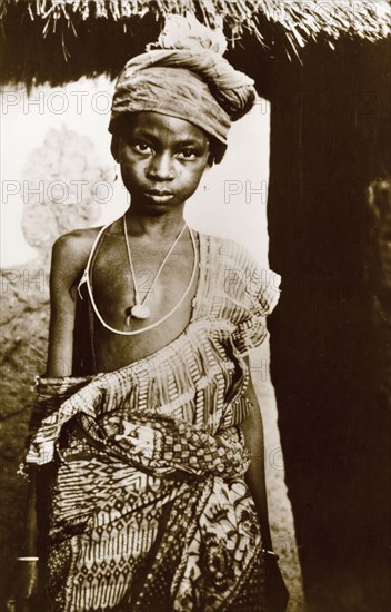 Portrait of a Hausa girl. Portrait of a young Hausa girl wearing traditional patterned robes and a head wrap. Nigeria, circa 1940. Nigeria, Western Africa, Africa.
