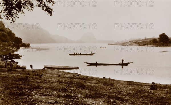 Juju Rock from the River Niger. Canoes float in the calm waters of the River Niger close to Juju Rock at Jebba, which is barely visible in the distance. Near Jebba, Kwara State, Nigeria, circa 1940., Kwara, Nigeria, Western Africa, Africa.