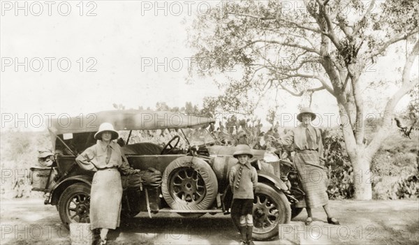 Preparing to embark on a journey. Two European women and a young boy pose beside a convertible car packed with luggage, ready to embark on a journey. India (Pakistan), circa 1930. Pakistan, Southern Asia, Asia.