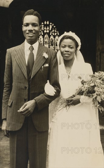 Titus and Oredola. A newlywed couple, Titus and Oredola, pose on the steps outside Freetown Cathedral following their Christian wedding ceremony. Freetown, Sierra Leone, 27 April 1954. Freetown, West (Sierra Leone), Sierra Leone, Western Africa, Africa.
