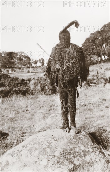 A dodo spirit man. Portrait of a Nigerian spirit man, dressed in a dodo masquerade costume that covers his head and face. Nigeria, circa 1940. Nigeria, Western Africa, Africa.