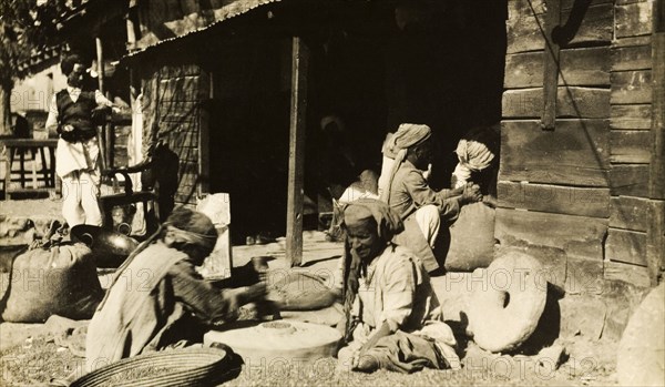 Indian millers at work. A group of men sit outdoors as they grind grain by hand using millstones. India, circa 1915., India, Southern Asia, Asia.