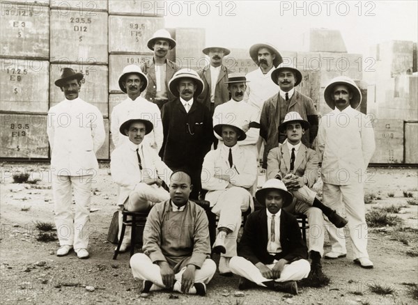 Civil engineers at the Hong Kong docks. A team of British and Chinese civil engineers pose for a group portrait. They were completing construction work at the Hong Kong docks under the supervision of Major Paul Dashwood (seated, centre). Hong Kong, China, 1919. Hong Kong, Hong Kong, China, People's Republic of, Eastern Asia, Asia.