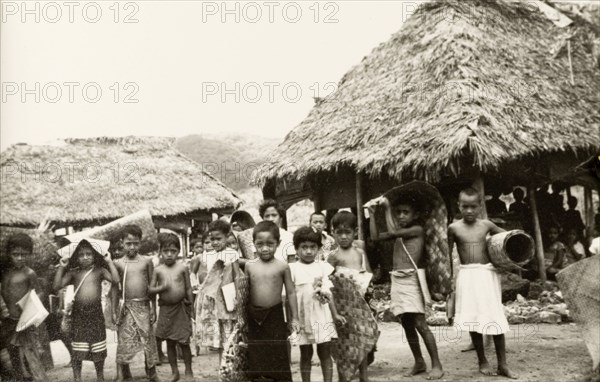 Samoan schoolchildren . A group of Samoan schoolchildren carry woven mats on their return home from school. Western Samoa (Samoa), circa 1956. Samoa, Pacific Ocean, Oceania.
