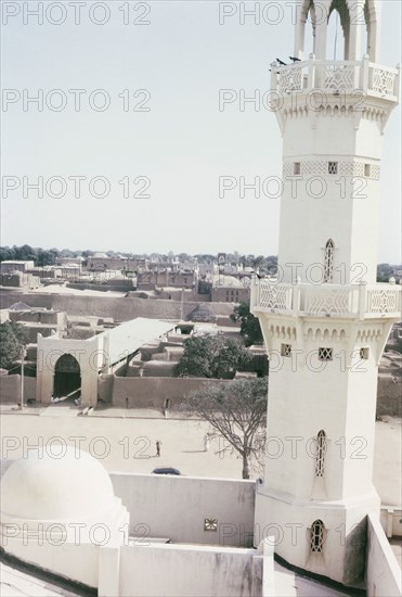 A minaret of Kano Central Mosque. View of a minaret at Kano Central Mosque and the town beyond. This mosque replaced another that was destroyed in the 1950s, and was built by the British government in gratitude for Nigeria's role during the Second World War (1939-45). Kano, Nigeria, October 1963. Kano, Kano, Nigeria, Western Africa, Africa.