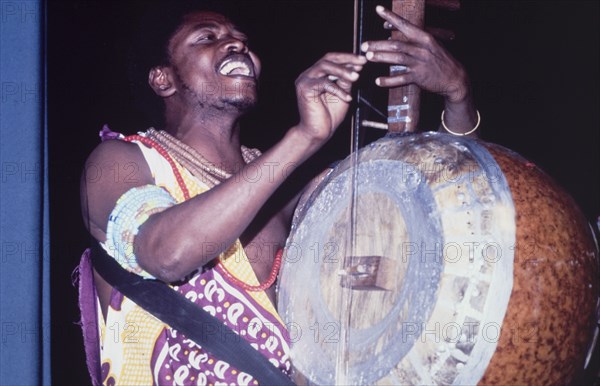 A lute player at the West African Music Village. A musician plays the lute at the West African Music Village, a cultural festival held at the Commonwealth Institute. London, England, 1989. London, London, City of, England (United Kingdom), Western Europe, Europe .