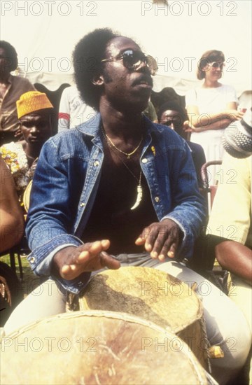 Drummer at the West African Music Village. A musician plays the drums at the West African Music Village, a cultural festival held at the Commonwealth Institute. London, England, 1989. London, London, City of, England (United Kingdom), Western Europe, Europe .