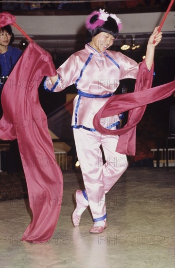 A traditional Chinese ribbon dance. A girl in traditional Chinese dress performs a dance with red ribbons during celebrations for the Chinese New Year. London, England, circa 1985. London, London, City of, England (United Kingdom), Western Europe, Europe .
