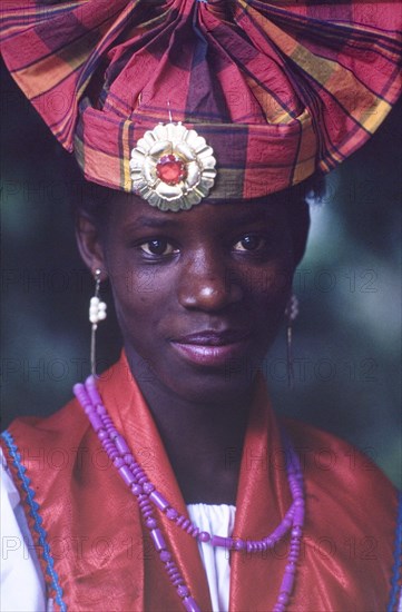 Dancer at the Caribbean Music Village. Head and shoulders portrait of a female dancer at the Caribbean Music Village, a cultural festival held at the Commonwealth Institute. She wears traditional Caribbean costume and jewellery including a fanned headdress decorated with a pin brooch. London, England, 7-26 July 1986. London, London, City of, England (United Kingdom), Western Europe, Europe .