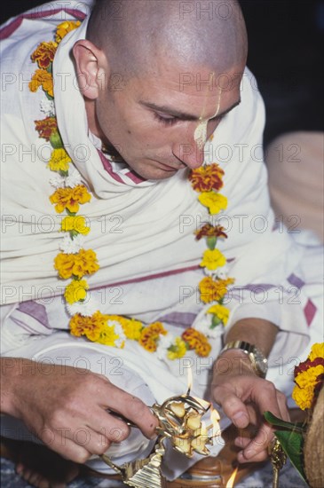 Lighting a candle for Lord Krishna. A member of the International Society for Krishna Consciousness, also known as the 'Hare Krishna' movement, lights a candle during a religious street festival. London, England, circa 1985. London, London, City of, England (United Kingdom), Western Europe, Europe .