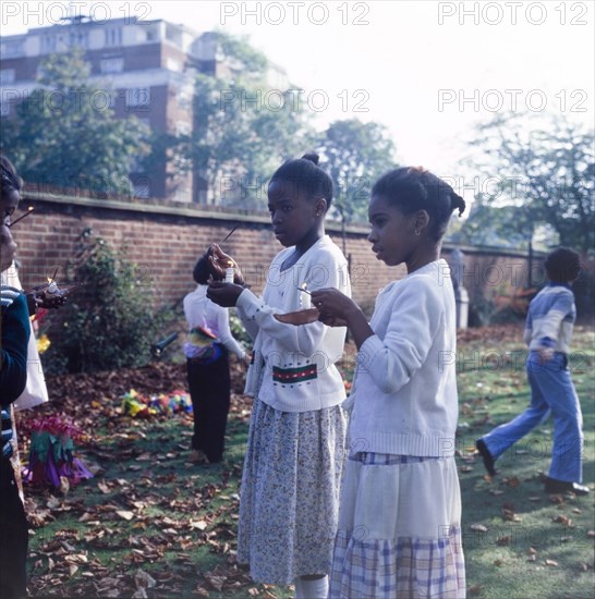 Lighting candles for Diwali. Two girls light candles outdoors to celebrate Diwali, the Hindu festival of light, during a mela (fair) at the Commonwealth Institute. London, England, circa 1985. London, London, City of, England (United Kingdom), Western Europe, Europe .