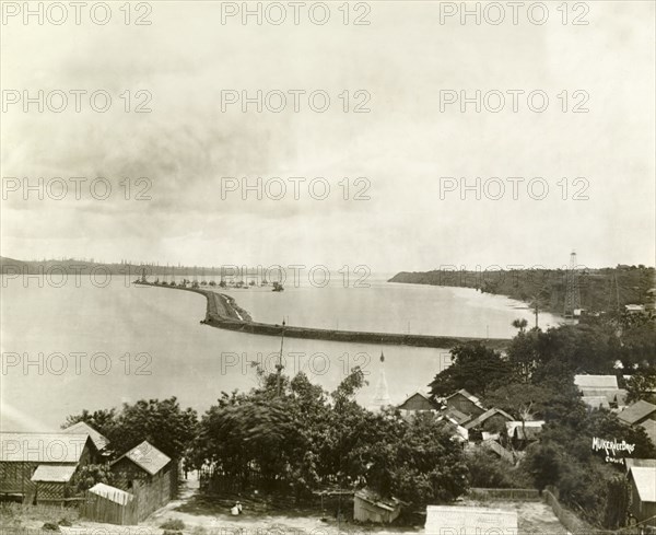 Defensive wall at the Chauk oil fields. View over the Ayeyarwady River at Chauk, showing an access road and defence wall during high water. The roofs of town buildings appear in the foreground, with a network of oil derricks in the distance. Chauk, Burma (Myanmar), circa 1930., Magway, Burma (Myanmar), South East Asia, Asia.