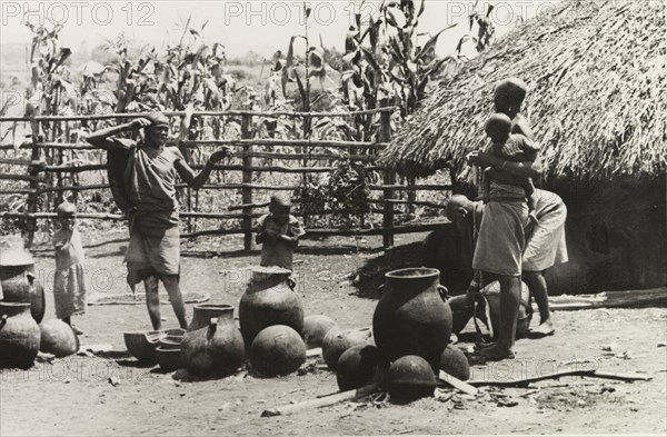 A Kikuyu family pottery'. Three Kikuyu women look after several small children as they make clay pots outdoors at a "family pottery". South Nyeri, Kenya, 1936. Nyeri, Central (Kenya), Kenya, Eastern Africa, Africa.