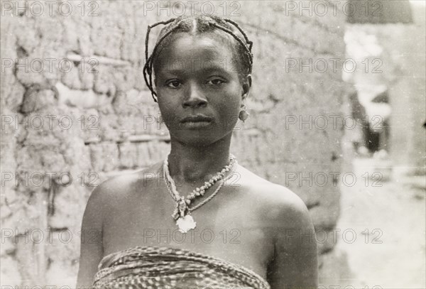 A young Asante woman. Head and shoulders portrait of a young Asante (Ashanti) woman. Her hair is braided and she wears delicate earrings with a beaded necklace. Gold Coast (Ghana), circa 1950. Ghana, Western Africa, Africa.