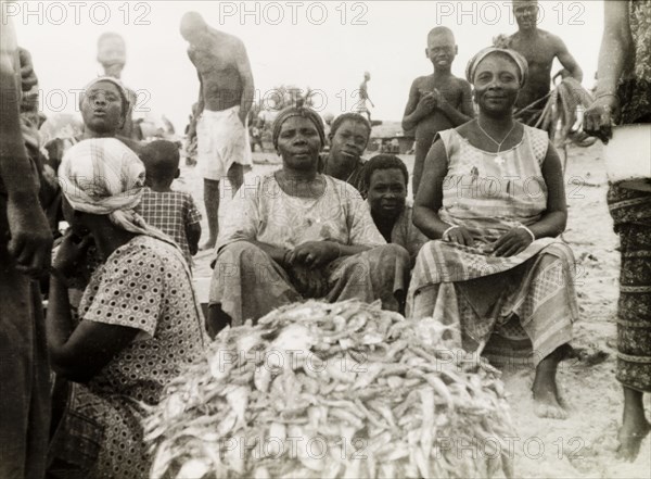 Fish stall at a Ghanaian market. Female traders sit beside a pile of freshly caught fish at a market stall in Elmina. Elmina, Gold Coast (Ghana), circa 1950. Elmina, Central (Ghana), Ghana, Western Africa, Africa.