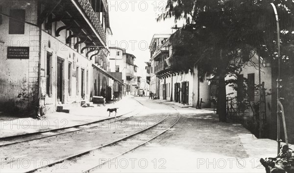 Quiet street in Mombasa. Tram lines run along the centre of a quiet street flanked by colonial-style buildings with balconies. Mombasa, British East Africa (Kenya), 1911. Mombasa, Coast, Kenya, Eastern Africa, Africa.