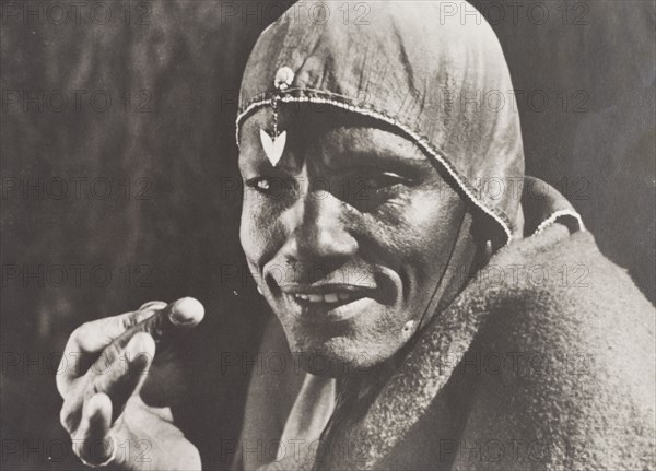 Kikuyu guide wearing a sheep's stomach cap. Close up shot of 'Gacheche', a guide who was assigned by Chief Murigo to look after Elspeth Huxley and her companions during their stay with the Kikuyu. He wears a cap made from a sheep's stomach, which is simply decorated with beads. Near Kakamega, Kenya, 1936. Kakamega, West (Kenya), Kenya, Eastern Africa, Africa.