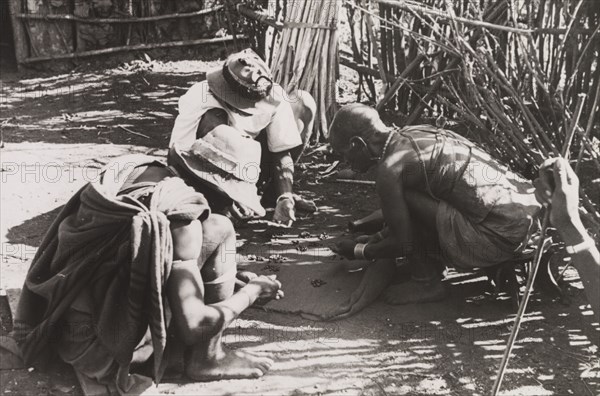 Kikuyu men reading their fortune. A group of Kikuyu men gather around to read their fortunes by scattering beans on the ground. South Nyeri, Kenya, circa 1936. Nyeri, Central (Kenya), Kenya, Eastern Africa, Africa.