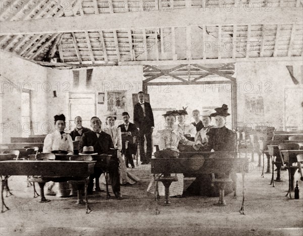American missionaries in a Jamaican school. A group of American missionaries sit or stand by desks in an empty schoolroom. Jamaica, circa 1890. Jamaica, Caribbean, North America .