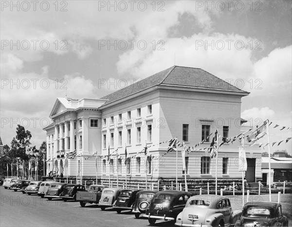 Decorations at Nairobi City Hall. Bunting hangs above a row of cars outside City Hall in celebration of a royal visit by Princess Elizabeth and the Duke of Edinburgh. Nairobi, Kenya, February 1952. Nairobi, Nairobi Area, Kenya, Eastern Africa, Africa.