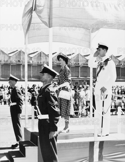 Taking the salute'. Princess Elizabeth and the Duke of Edinburgh stand on a dais to receive a welcome salute, shortly after arriving at Eastleigh Airport for their royal visit to Kenya. Nairobi, Kenya, February 1952. Nairobi, Nairobi Area, Kenya, Eastern Africa, Africa.