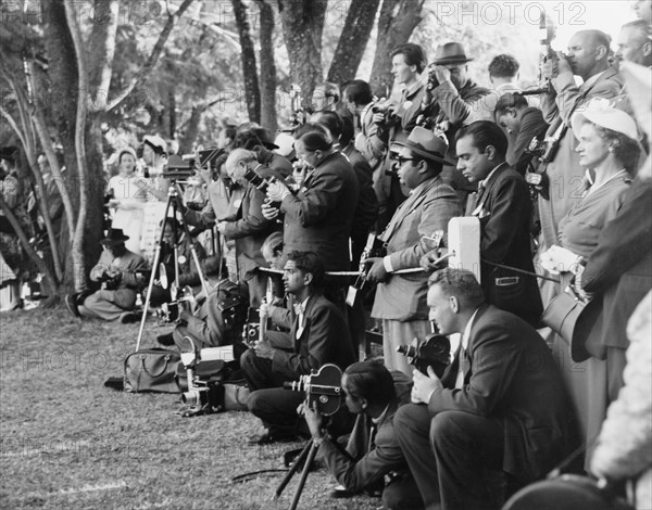 Press at a royal garden party. Photographers and journalists assemble in the grounds of Government House to cover an official garden party attended by Princess Elizabeth and the Duke of Edinburgh on their royal visit to Kenya. Nairobi, Kenya, February 1952. Nairobi, Nairobi Area, Kenya, Eastern Africa, Africa.
