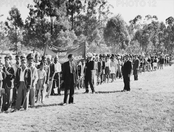 Asian students arrive at Government House. A long line of Asian high school students arrive at Government House to greet Princess Elizabeth and the Duke of Edinburgh during their royal tour of Kenya. They carry a banner, which reads: 'Loyal greetings from Govt. Asian High School'. Nairobi, Kenya, February 1952. Nairobi, Nairobi Area, Kenya, Eastern Africa, Africa.