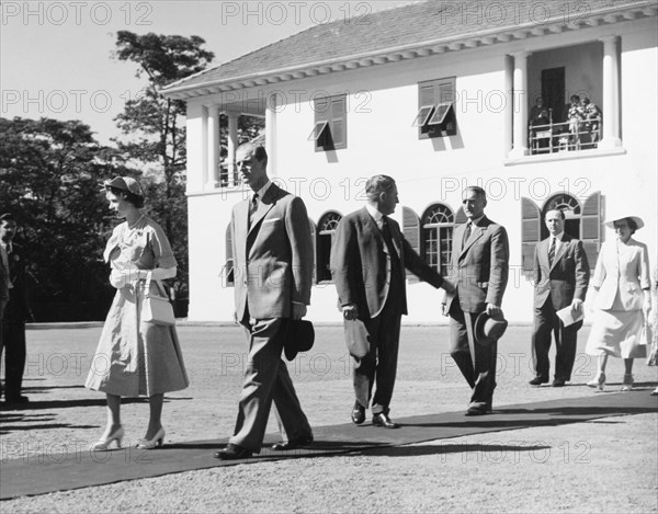 The royal couple leave Government House. Princess Elizabeth and the Duke of Edinburgh walk along a red carpet as they leave Government House following an official reception to start their royal tour of Kenya. Nairobi, Kenya, February 1952. Nairobi, Nairobi Area, Kenya, Eastern Africa, Africa.